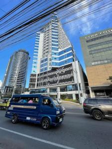a blue van driving down a city street with tall buildings at Davao City Serenity on Seventeenth One-Bedroom Condo beside Shopping Malls with Seaview and City view in Davao City
