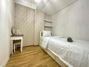 een witte slaapkamer met een bed en een bureau bij Gateway Pasteur Apartment by RumahKu in Bandung