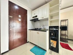 een keuken met witte kasten en een bruine deur bij Gateway Pasteur Apartment by RumahKu in Bandung