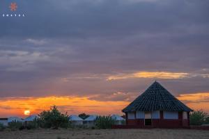 a hut on the beach with a sunset in the background at Zostel Sam Desert (Jaisalmer) in Sām