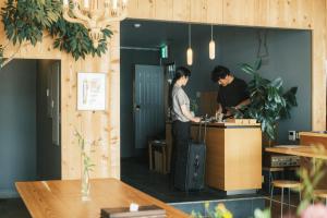 zwei Männer stehen an einem Schalter in einem Büro in der Unterkunft Okazaki Micro Hotel ANGLE in Okazaki