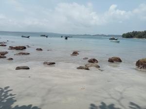 a beach with rocks and boats in the water at Kutnalek Surf Camp Siberut Mentawai front Beach,Green Village,front Wave for surfing in Masokut