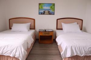 um quarto com duas camas e uma mesa entre elas em Tinian Lucky Home em Tinian