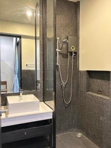 La salle de bains est pourvue d'un lavabo et d'une douche. dans l'établissement O2 The Residence โอทู เดอะ เรสซิเดนซ์, à Kanchanaburi
