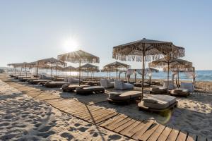 a row of umbrellas and lounge chairs on a beach at Pnoe Breathing Life - Adults Only in Karteros