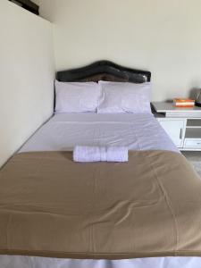 ein Bett mit einer braunen Decke und weißen Kissen in der Unterkunft D'Liwatan Bungalow in Masbagik