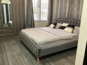 um quarto com uma cama grande com lençóis brancos e almofadas em Fine Boy Villa, Luxe Two-Bedroom Apartments in Tema Community 25 em Tema