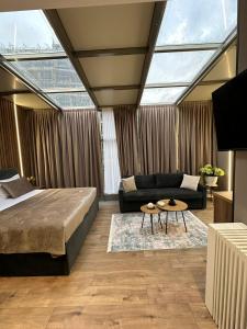 a bedroom with a bed and a couch and a table at Hotel Vila Verde City Center in Tirana