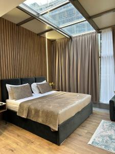 a bedroom with a large bed with a large window at Hotel Vila Verde City Center in Tirana