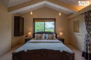 a bedroom with a large bed and a window at River Song by VEO - Part of StayVista in Lonavala