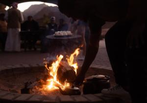a person standing over a fire in a fire pit at Rum Planet Camp in Wadi Rum