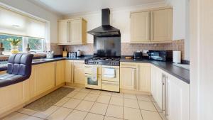 a kitchen with yellow cabinets and a stove top oven at Charming 5-Bed House in Grays in Grays Thurrock