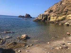 a beach with rocks and water and a mountain at Oasi del Relax - Seaside Peaceful Panoramic Terrace in ITALY - new Sardinia apartment 50 mt beach&sea full comfort air conditioning-WiFi-Parking-Privacy in Torre Dei Corsari