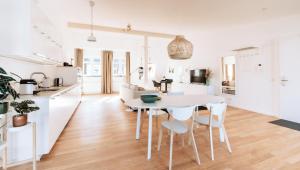 a white kitchen and living room with a table and chairs at Deichstadt Apartments in Neuwied