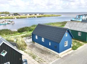 une maison bleue avec un toit noir à côté d'une masse d'eau dans l'établissement Harbour Living, à Hvide Sande