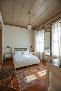 een slaapkamer met een wit bed en een spiegel bij Elia Hotel Cunda by Ortunc in Ayvalık