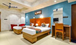 a bedroom with two beds and a desk in it at FabHotel Siddharth Corporate in Gandhinagar