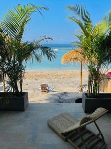 una spiaggia con una sedia, palme e l'oceano di La Plage Classique Beachfront Nusa Penida a Nusa Penida