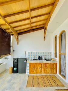 a kitchen with wooden cabinets and a stainless steel refrigerator at La Plage Classique Beachfront Nusa Penida in Nusa Penida