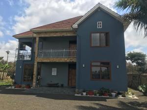 a blue house with a balcony on top at Lerai X Desty in Arusha
