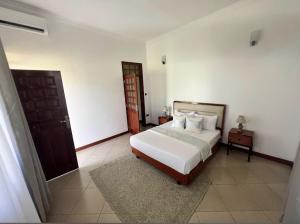 1 dormitorio con 1 cama y puerta de madera en Lerai X Desty, en Arusha