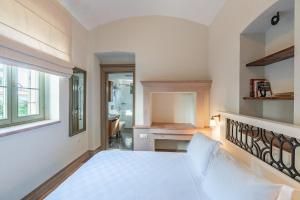 a white bedroom with a bed and a desk at Elia Hotel Cunda by Ortunc in Ayvalık