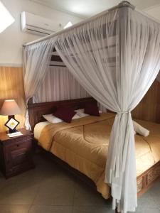 a bedroom with two beds and a canopy with curtains at Nitya Home Stay Lembongan in Nusa Lembongan