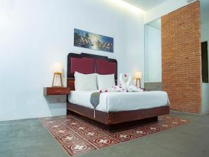 ein Schlafzimmer mit einem großen Bett und einer Ziegelwand in der Unterkunft Tanei Angkor Resort and Spa in Siem Reap