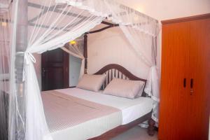 a bedroom with a canopy bed with white sheets and pillows at Winsi Villa in Unawatuna