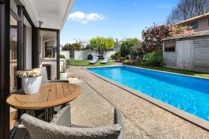 a swimming pool with a table and chairs next to a house at Hamilton Summer Treat- 4 Bedroom with pool in Hamilton