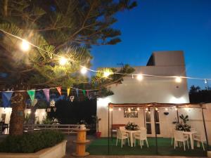 un patio con mesa y sillas por la noche en B&B il MENHIR, en Lequile