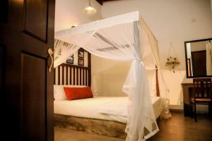 a bedroom with a white bed with a canopy at The villaRo in Hikkaduwa