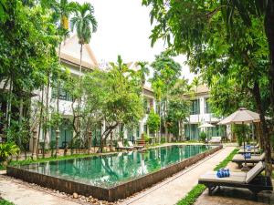 a swimming pool in front of a building with trees at Tanei Angkor Resort and Spa in Siem Reap