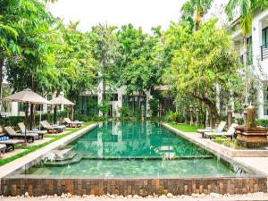 a swimming pool in front of a building with trees at Tanei Angkor Resort and Spa in Siem Reap