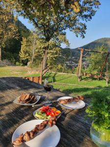 uma mesa com pratos de comida e um copo de vinho em Хижа Гора em Shaian