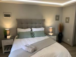 una camera da letto con un grande letto bianco con due lampade di Footprints Self Catering Solar No Loadshedding a Lanseria