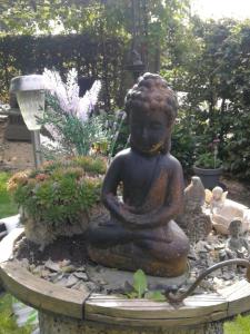 a statue of a meditating person in a garden at Het Huisje in Bergen op Zoom
