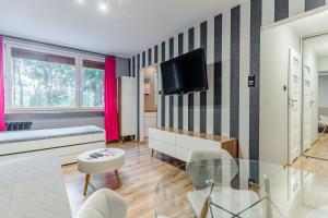 a living room with a couch and a tv on a wall at Apartament Black Stripes blisko morza in Gdańsk
