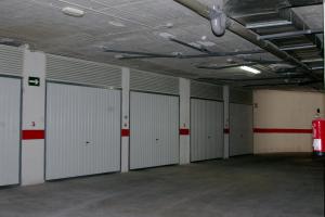a row of garage stalls with white garage doors at Apartamentos Les Dunes Centro in Benidorm