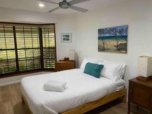 a bedroom with a white bed with a ceiling fan at Absolute Beach Front Home -Dogs, Surf, Relax, Bush in Kawana Waters