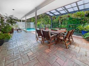 a patio with a table and chairs and a pool at Absolute Beach Front Home -Dogs, Surf, Relax, Bush in Kawana Waters