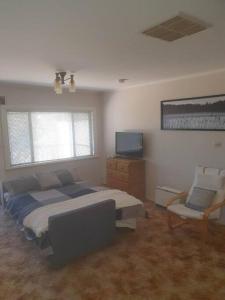 a bedroom with a bed and a tv and a chair at The House with the Purple Gate in Broken Hill
