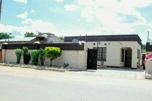 un bâtiment blanc avec un toit noir dans l'établissement The CabinGuesthouse, à Gaborone