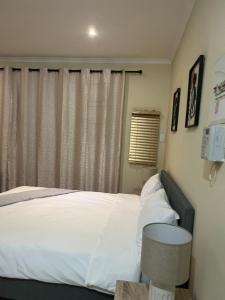 a bedroom with a bed with white sheets and a window at The small-haven in Polokwane