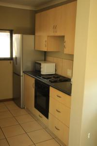 a kitchen with wooden cabinets and a stove and a microwave at The small-haven in Polokwane