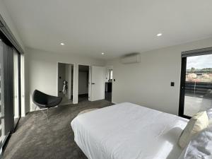 1 dormitorio con 1 cama blanca y 1 silla en Royal Residency, en Auckland