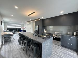a kitchen with black cabinets and a counter with stools at Royal Residency in Auckland