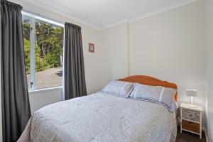 a bedroom with a bed and a large window at Takamatua Holiday Home in Takamatua Bay