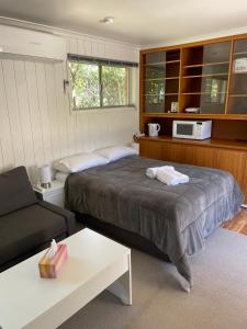 a bedroom with a bed and a couch and a microwave at Canberra Hospital Locum Welcome in Harman