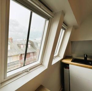 eine Küche mit einem Fenster mit Blick auf ein Gebäude in der Unterkunft Villa Beauregard in Mers-les-Bains